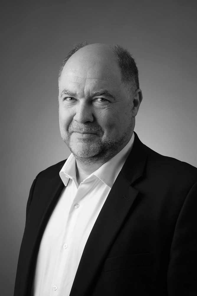 Portrait professionnel en noir et blanc d'un homme en veste sombre et chemise blanche.
