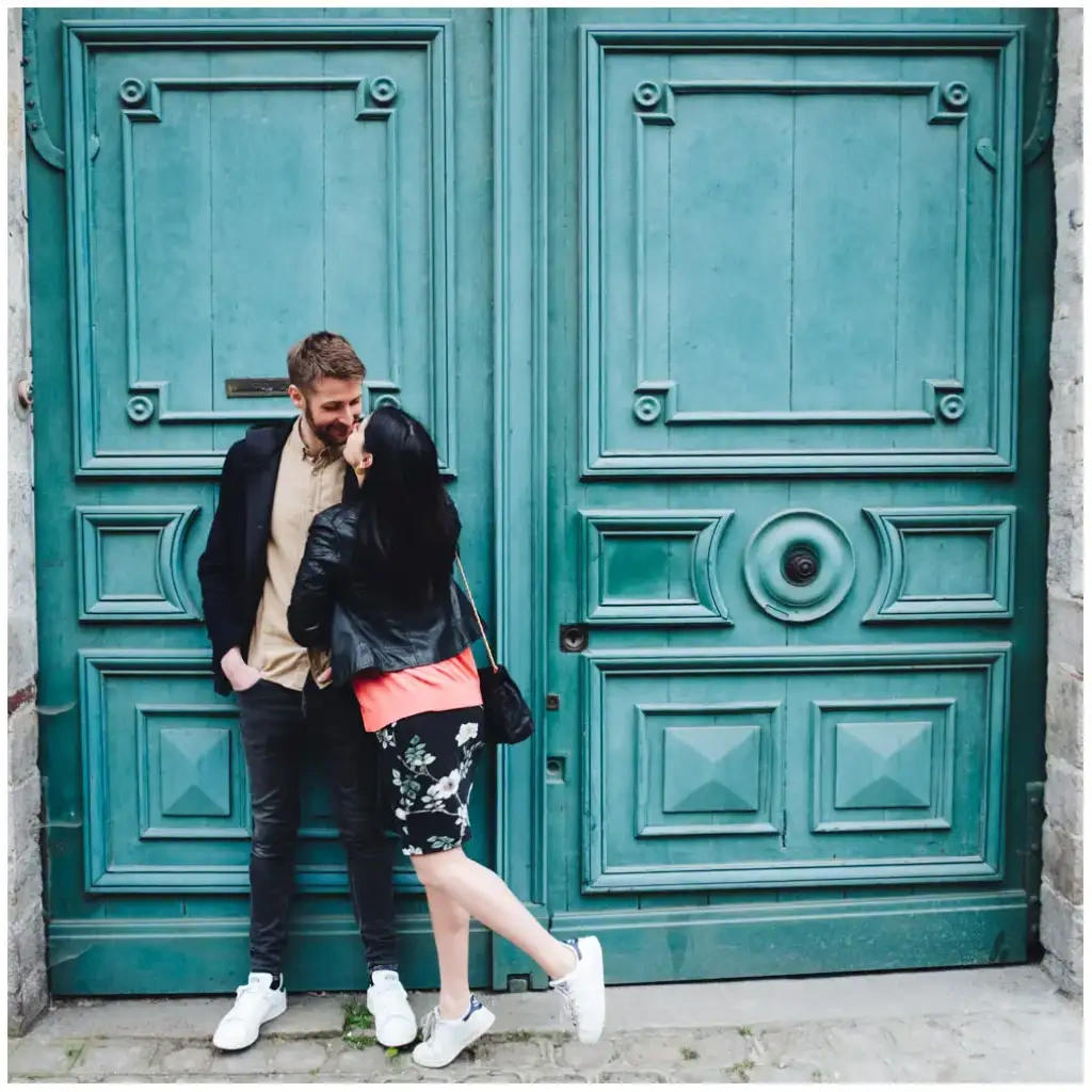 Couple complice devant une grande porte turquoise lors d’une séance photo lifestyle.