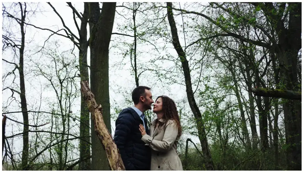 Couple échangeant un baiser pendant une promenade en forêt.