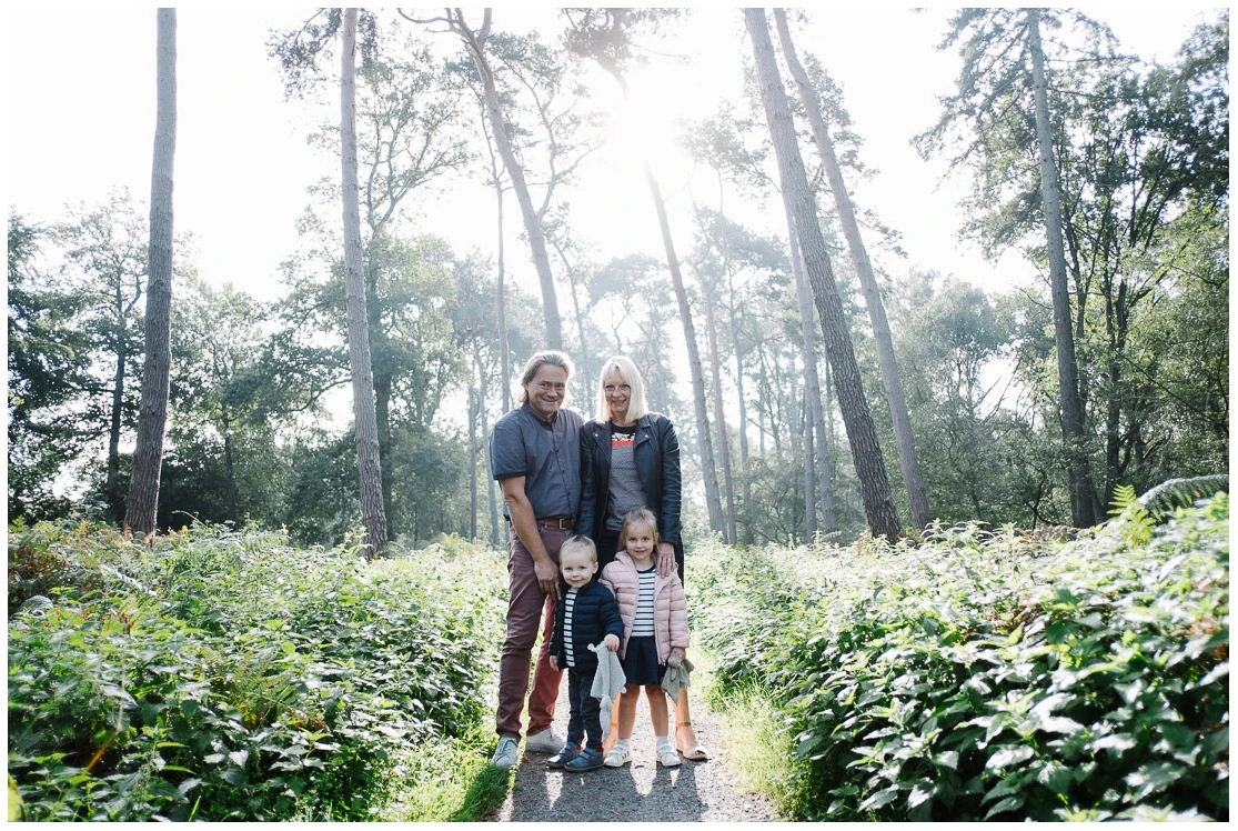 Deux adultes et deux jeunes enfants réunis sur un chemin dans une forêt lumineuse.
