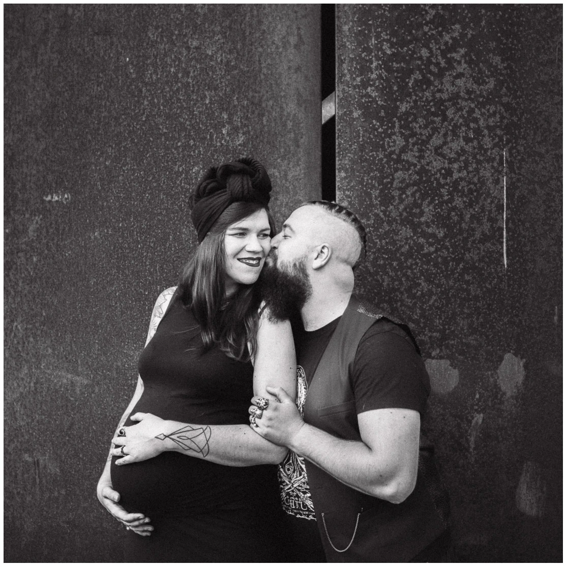 Couple complice pendant une séance photo de grossesse en noir et blanc.