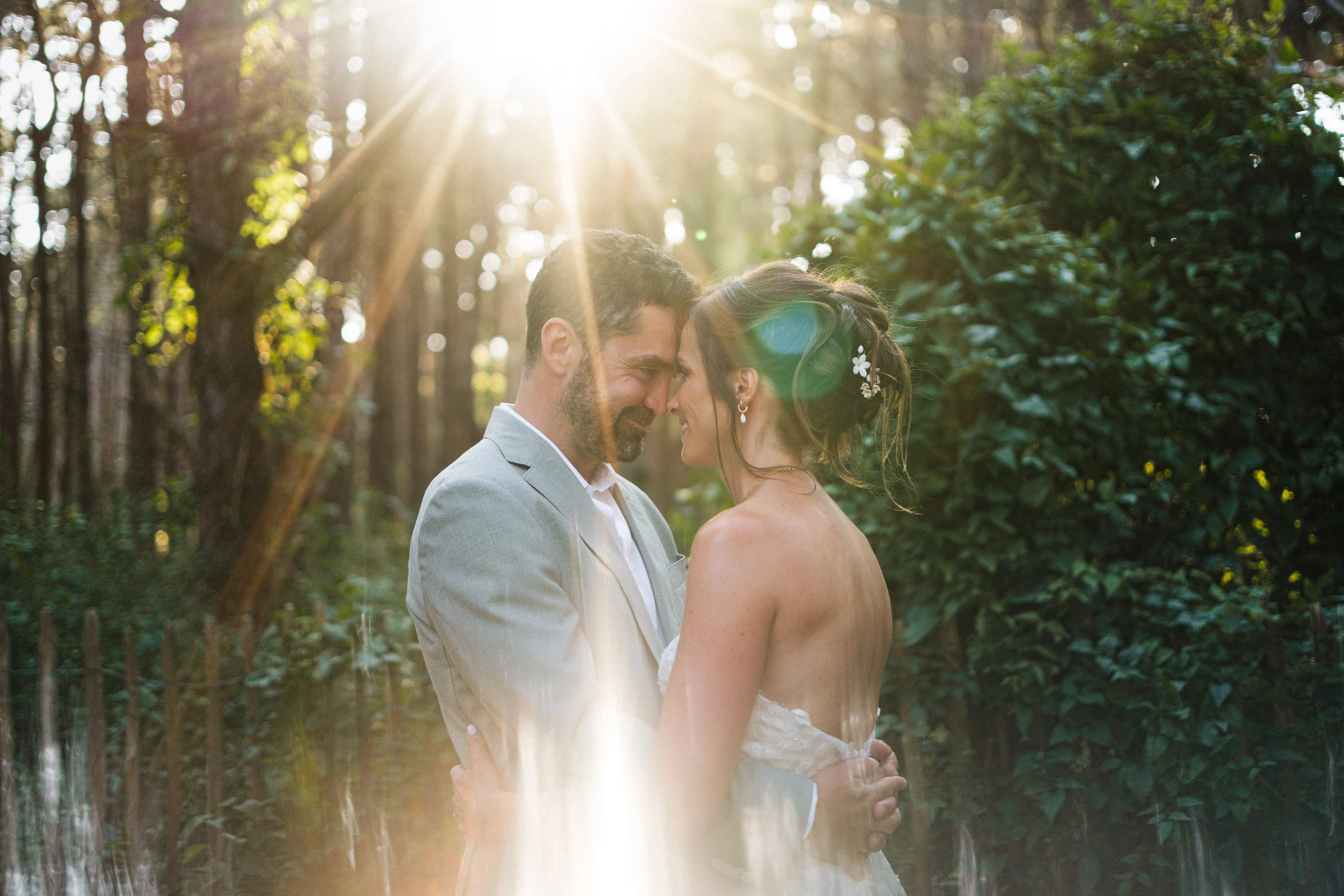 Caroline et Anthony front contre front dans une forêt traversée par une lumière dorée.