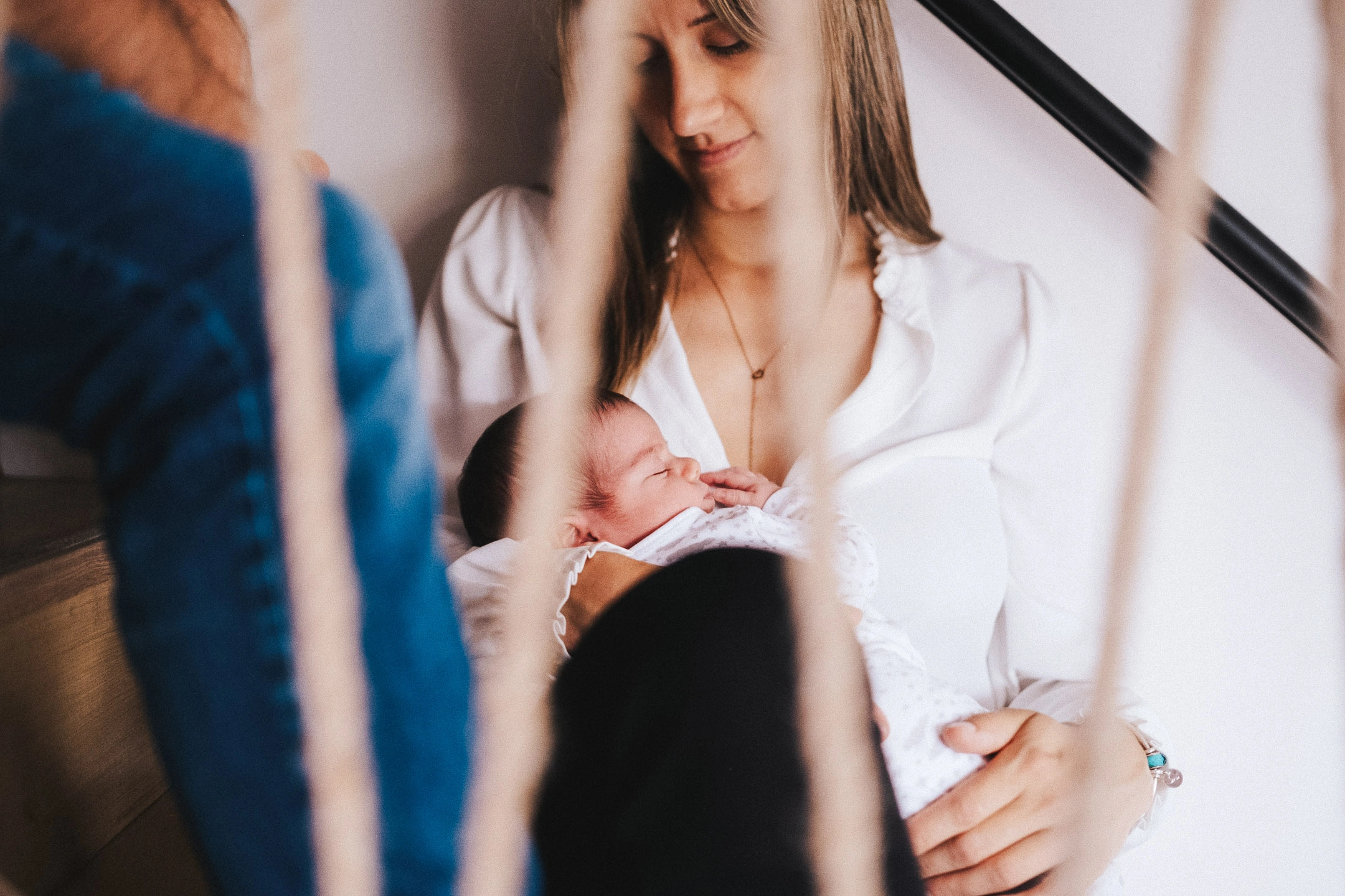 Une mère tient son nouveau-né endormi dans ses bras, photographiée à travers un reflet.