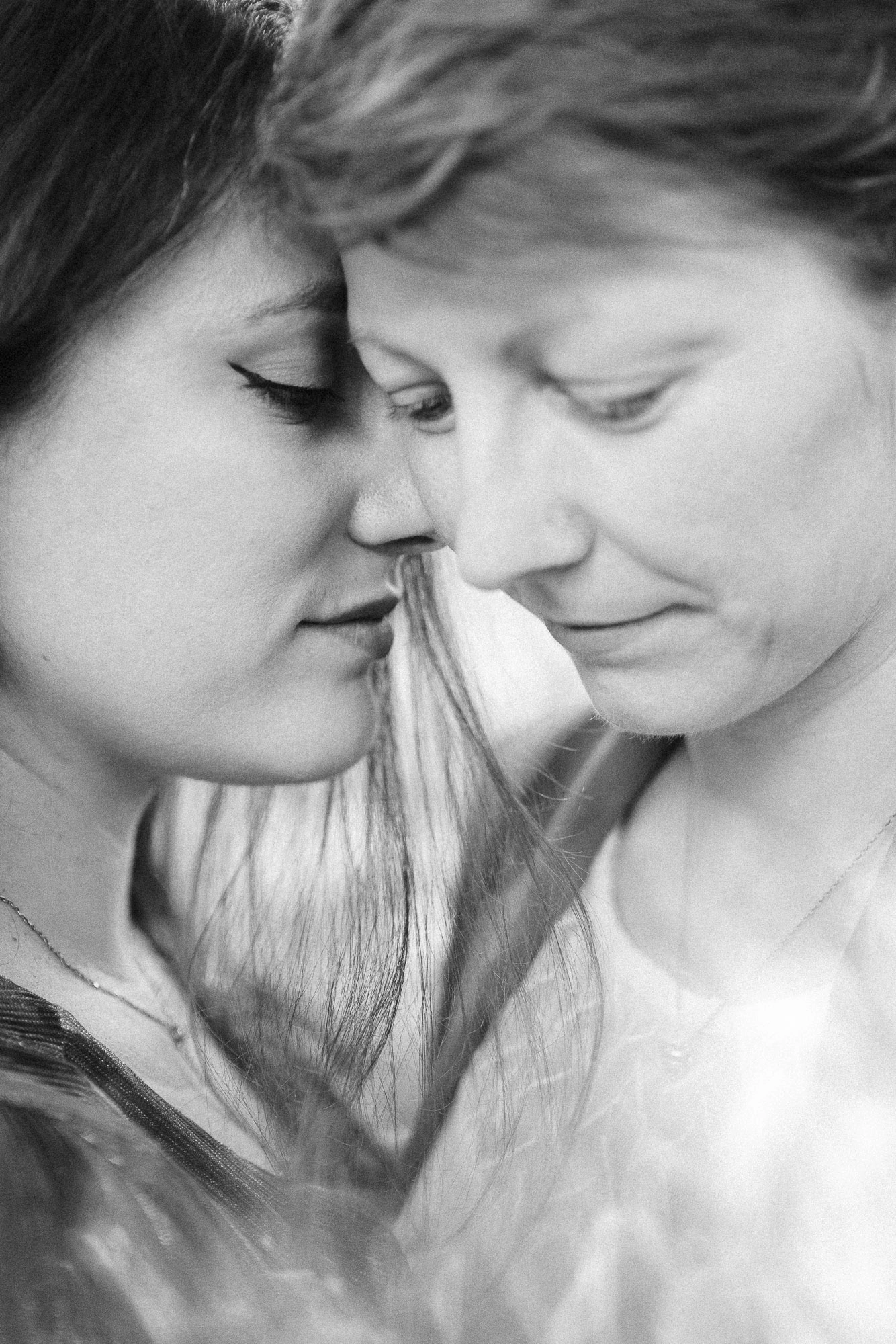Portrait en noir et blanc de deux femmes rapprochant leurs visages, les yeux fermés.