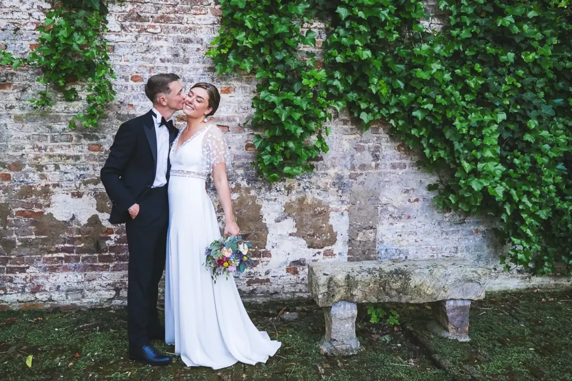 Portrait de Célia et Louis devant un mur de briques couvert de lierre.