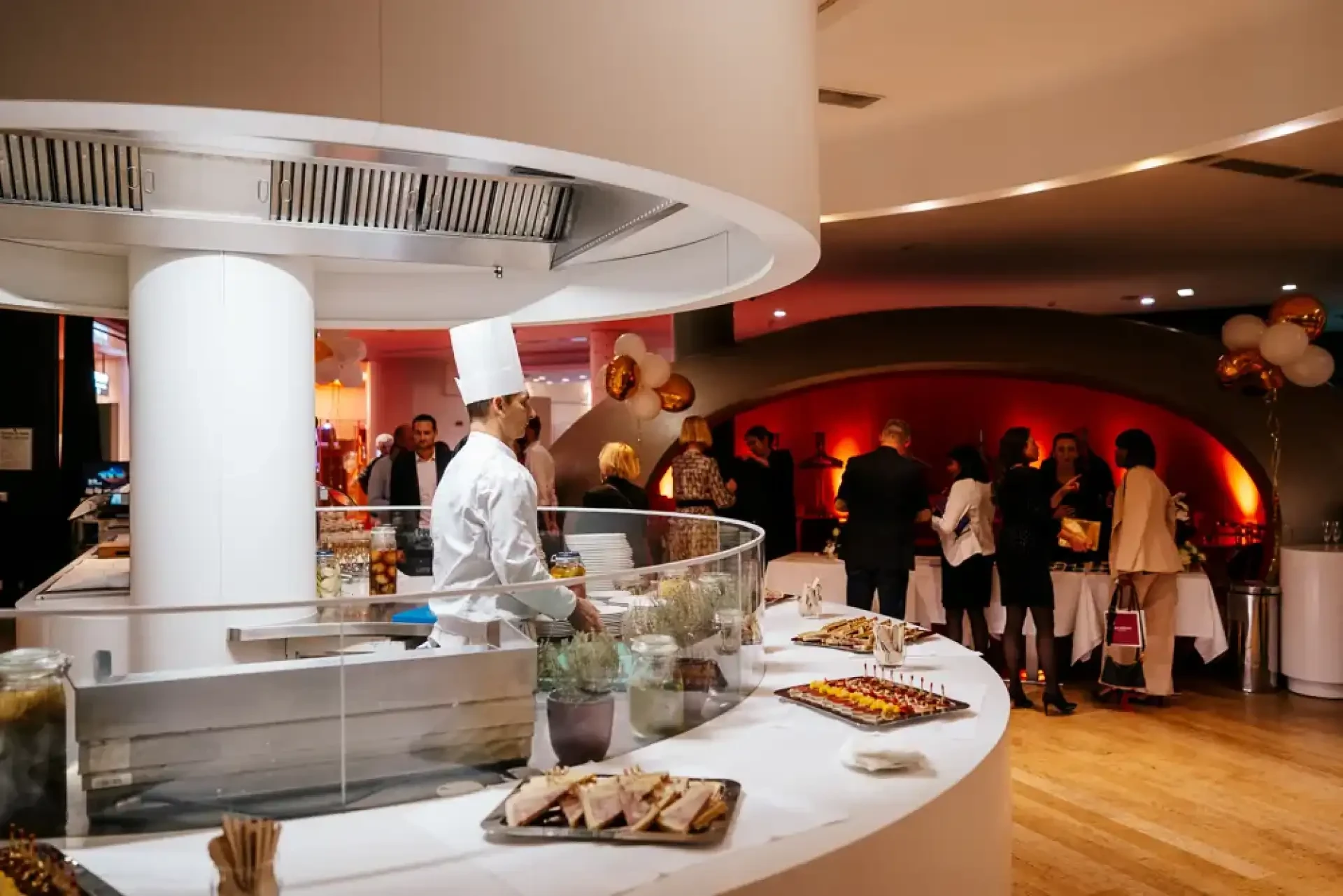 Chef en veste blanche devant un buffet pendant une réception professionnelle.