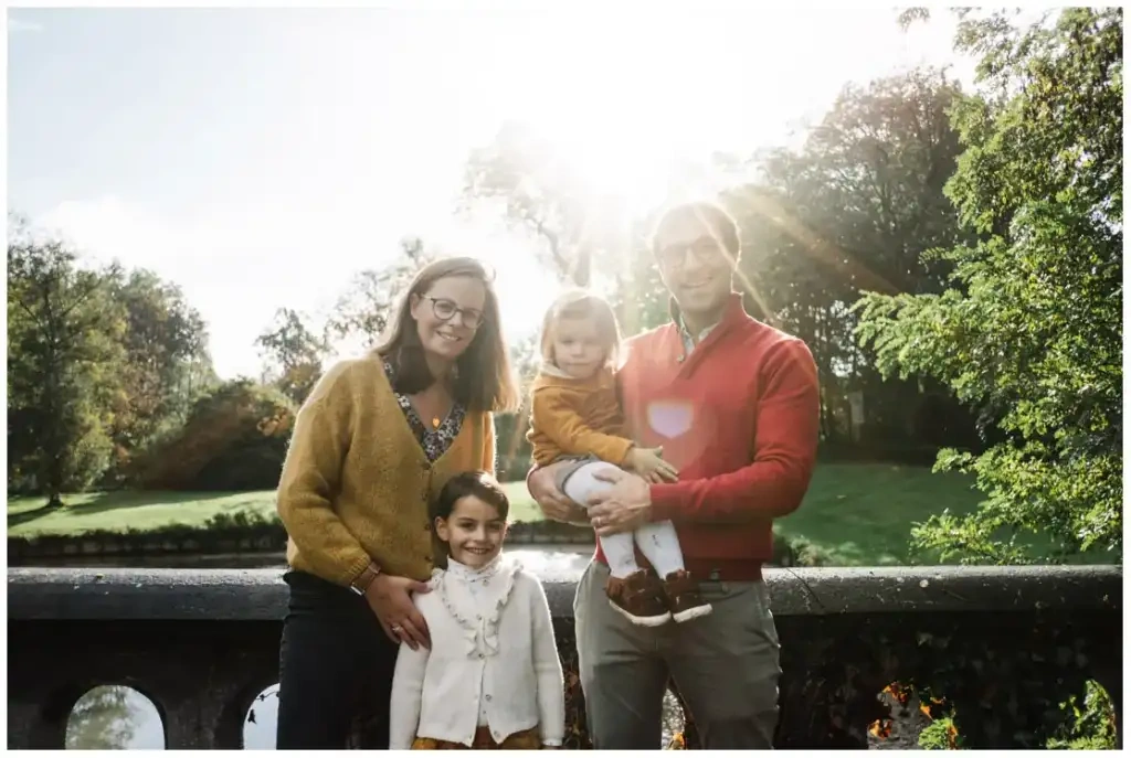 Deux parents et leurs deux filles posent près d’un muret dans une lumière solaire rasante.