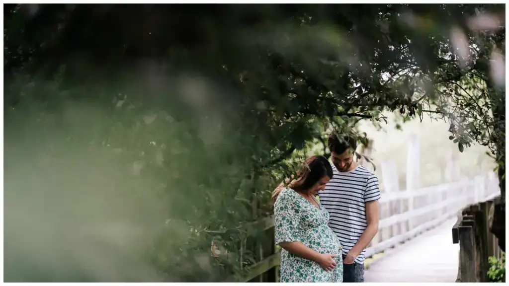 Un couple attend un enfant sur une passerelle bordée de végétation.