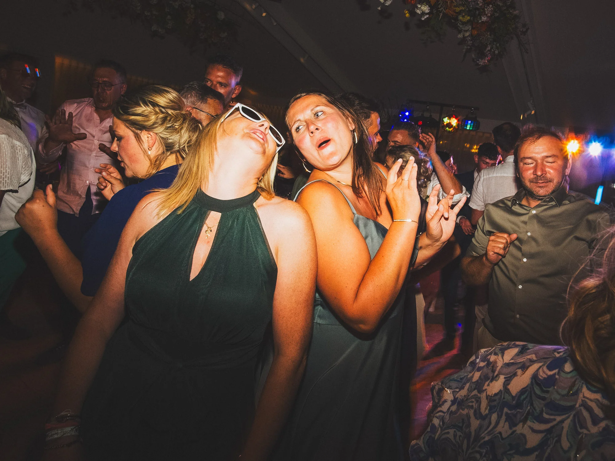 Invités dansant sur une piste éclairée par des lumières colorées pendant une soirée de mariage.